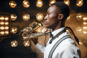 Obraz premium Black jazz performer poses with saxophone on stage