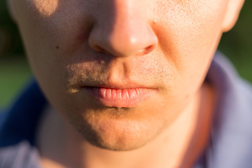 Close Up Of Man's Face Lips. Portrait of a young man on nature background. Emotion facial expression.