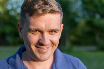 Portrait of a young man on nature background. Emotion facial expression. Smug smile, feelings and people reaction. Murderous psycho smile. crazy Killer lunatic man grinning.