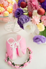 Obraz na płótnie Canvas baby pink booties and a hair hoop on a background of cupcakes and flowers