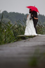 Hochzeitspaar auf Bootsteg im Regen