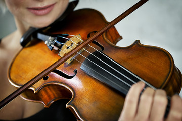 Violin and a fiddlestick close up in hands of a young female violinist during music performance
