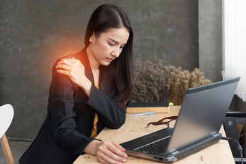 Image of young office woman  shoulder pain while sitting at working desk,concept office syndrome.