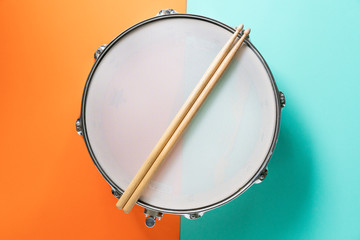 Fototapeta na wymiar Drum stick on color table background, top view, music concept