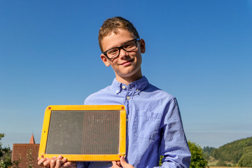 Boy with arithmetic problems on a blackboard with glasses in front of a blue sky