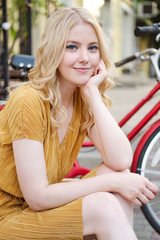 Fototapeta na wymiar Portrait of beautiful romantic blond girl in dress dreamily looking in camera on street