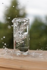 A transparent glass with water, a stone with the inscription 