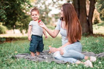  Mother with son blowing soap bubbles in the park.