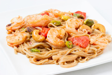 Soba noodles with vegetables , shrimps and cashew on a white plate. Asian food creative concept.
