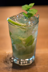 Refreshing mint cocktail mojito with rum and lime, cold drink or beverage with ice on white wooden background, top view