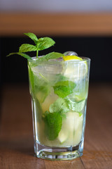 Refreshing mint cocktail mojito with rum and lime, cold drink or beverage with ice on white wooden background, top view