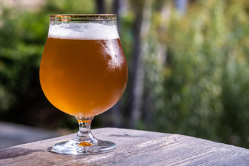 glass with beer on a wooden table on a sunny day
