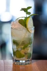 Refreshing mint cocktail mojito with rum and lime, cold drink or beverage with ice on white wooden background, top view