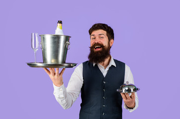 Waiter. Restaurant serving. Handsome waiter with serving tray and wine cooler. Waiter in restaurant carrying metal cloche lid cover and ice bucket with bottle, glass. Professional waiter in uniform.