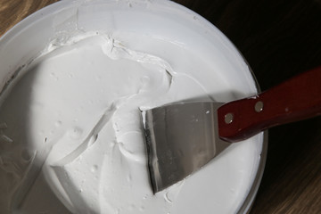 Man plastering wall with putty-knife, close up image. Fixing wall surface and preparation for...
