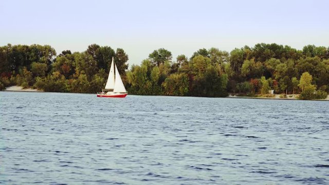 Yacht with open sail is traveling through the river
