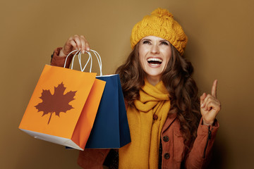 woman with autumn shopping bags pointing up at copy space