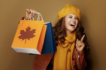 cheerful woman with autumn shopping bags isolated on beige