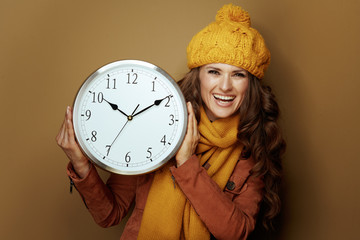 happy woman showing round clock remind about autumn time change