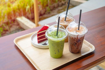 Top view of green tea ice with milk, espresso coffee ,chocolate milk and strawberry cake on wooden tray with warm light tone. Drink and dessert in coffee shop. food for relax and fresh concept.