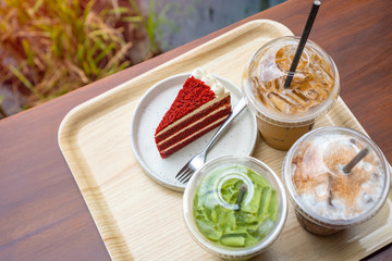 Top view of green tea ice with milk, espresso coffee ,chocolate milk and strawberry cake on wooden tray with warm light tone. Drink and dessert in coffee shop. food for relax and fresh concept.