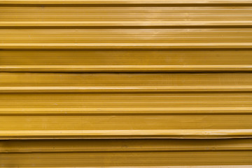 Horizontal corrugated fence of yellow metal sheets. Texture of metal fence picket Profile decking.