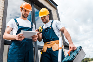 low angle view of handsome repairmen looking at digital tablet