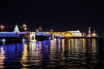 Fototapeta na wymiar Palace Bridge across the Neva River. Night city lights, ripples, colorful reflection in water. Cityscape with Kunstkamera building. Saint Petersburg, Russia