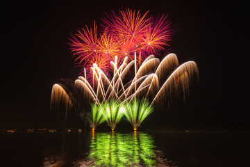 Feuerwerk an einem See spiegelt sich im Wasser