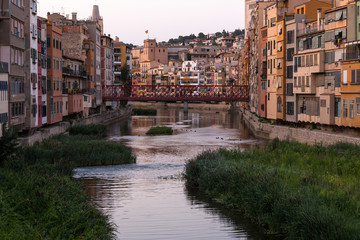 Colorful yellow and orange houses reflected in water river Onyar, in Girona, Catalonia, Spain.