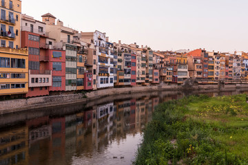 Colorful yellow and orange houses reflected in water river Onyar, in Girona, Catalonia, Spain.