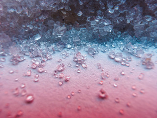 Heap of transparent white sugar crystals in mixed colour light. Macro photo