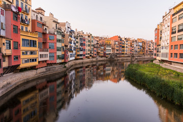Naklejka na ściany i meble Colorful yellow and orange houses reflected in water river Onyar, in Girona, Catalonia, Spain.