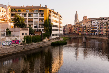 Colorful yellow and orange houses reflected in water river Onyar, in Girona, Catalonia, Spain.