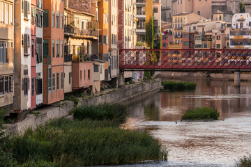 Colorful yellow and orange houses reflected in water river Onyar, in Girona, Catalonia, Spain.
