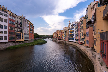 Colorful yellow and orange houses reflected in water river Onyar, in Girona, Catalonia, Spain.