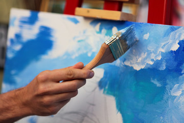 Artist paints a picture of oil paint brush in hand close up.Selective focus