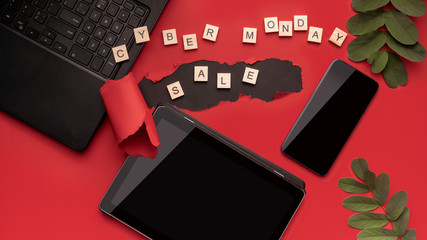 Laptop smartphone and tablet on a red background on the day of discounts. Black friday and cyber day concept. With wooden letters and inscription.