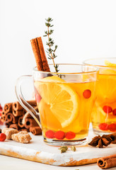 Winter or autumn healing hot tea with lemon, cranberries, thyme and spices, white background, copy space, selective focus