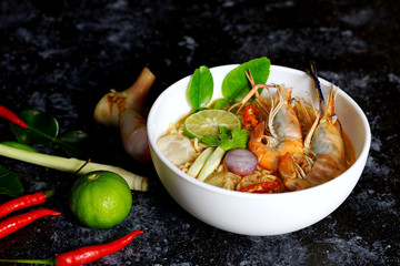 Spicy instant noodles soup with shrimp (tom yum kung) on dark background