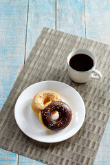 Donuts and coffee on wooden table. Top view with copy space.