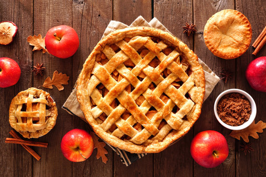 Homemade autumn apple pies, overhead view table scene with a rustic wood background