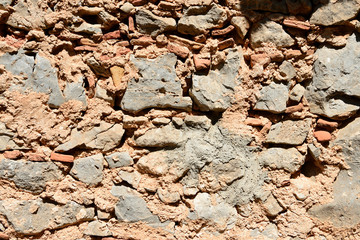 Fragment of an ancient wall illuminated by the bright sun close-up. Stone wall background.