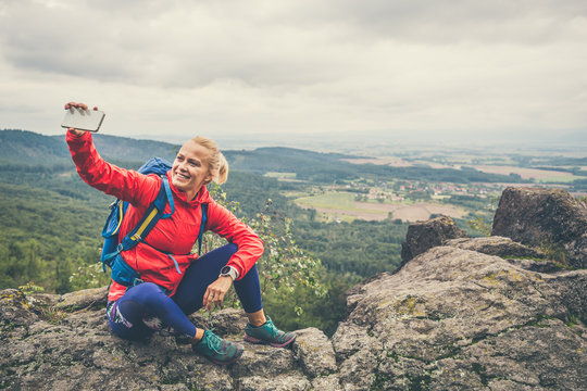Hiking woman with backpack taking photo with smartphone