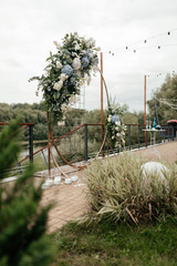 Circle wedding arc with blue and white flowers behind other plants in the foreground