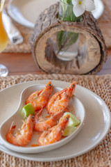 Fototapeta na wymiar Shrimps shelled fried in garlic and oil, served on white plate garnished with lime green.