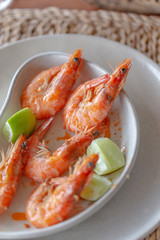Shrimps shelled fried in garlic and oil, served on white plate garnished with lime green.