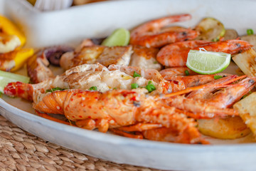 Grilled seafood with lobster, shrimp, squid and fish, accompanied by various vegetables.
