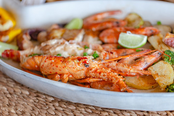 Grilled seafood with lobster, shrimp, squid and fish, accompanied by various vegetables.