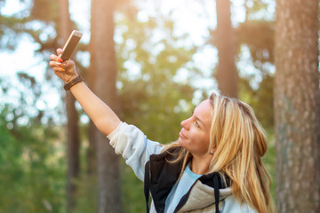 Beautiful happy sexy girl takes a selfie on the phone in nature in the forest in autumn.